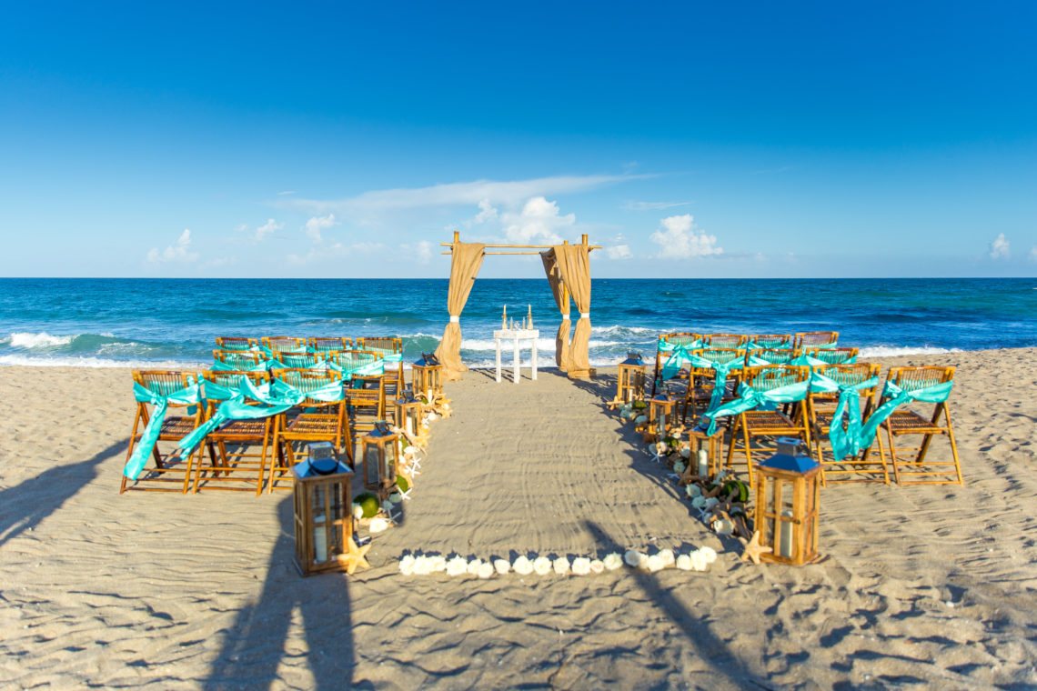 Wedding Setup on Jensen Beach, Florida with blue ocean, sand, brown chairs with tiffany blue sashes, and seashells.