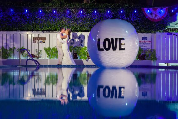 Beachside Village Resort, Florida, Wedding Reception - A Couple Embraces in front of a pool with a giant beach ball that reads "love"