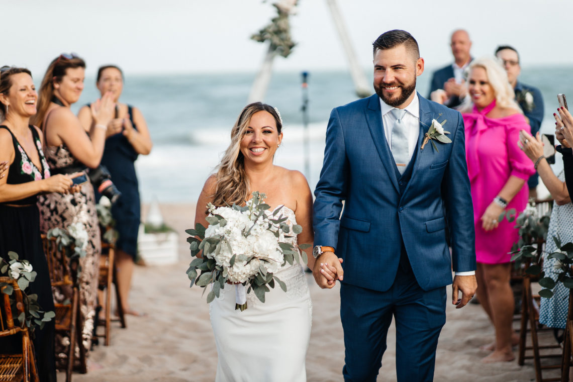 Bride and groom walk down the aisle with guests smiling and clapping - Lauderdale-by-the-Sea beach wedding