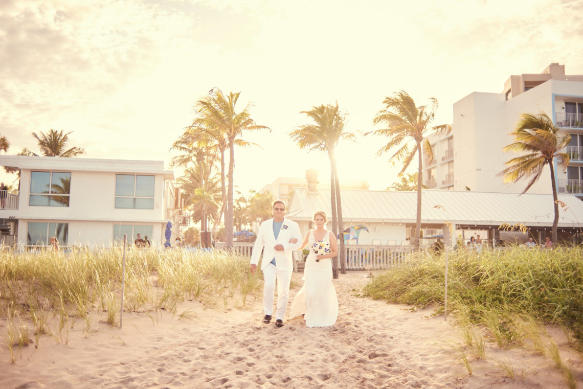 Bride walks down the aisle on the beach arm-in-arm with her father, Lauderdale-by-the-Sea