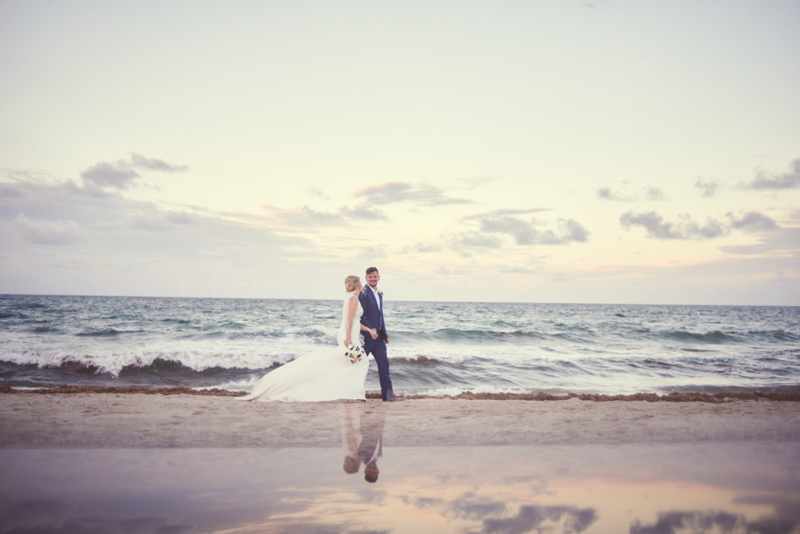 Bride and groom stroll along the beach in Lauderdale-by-the-Sea at sunset