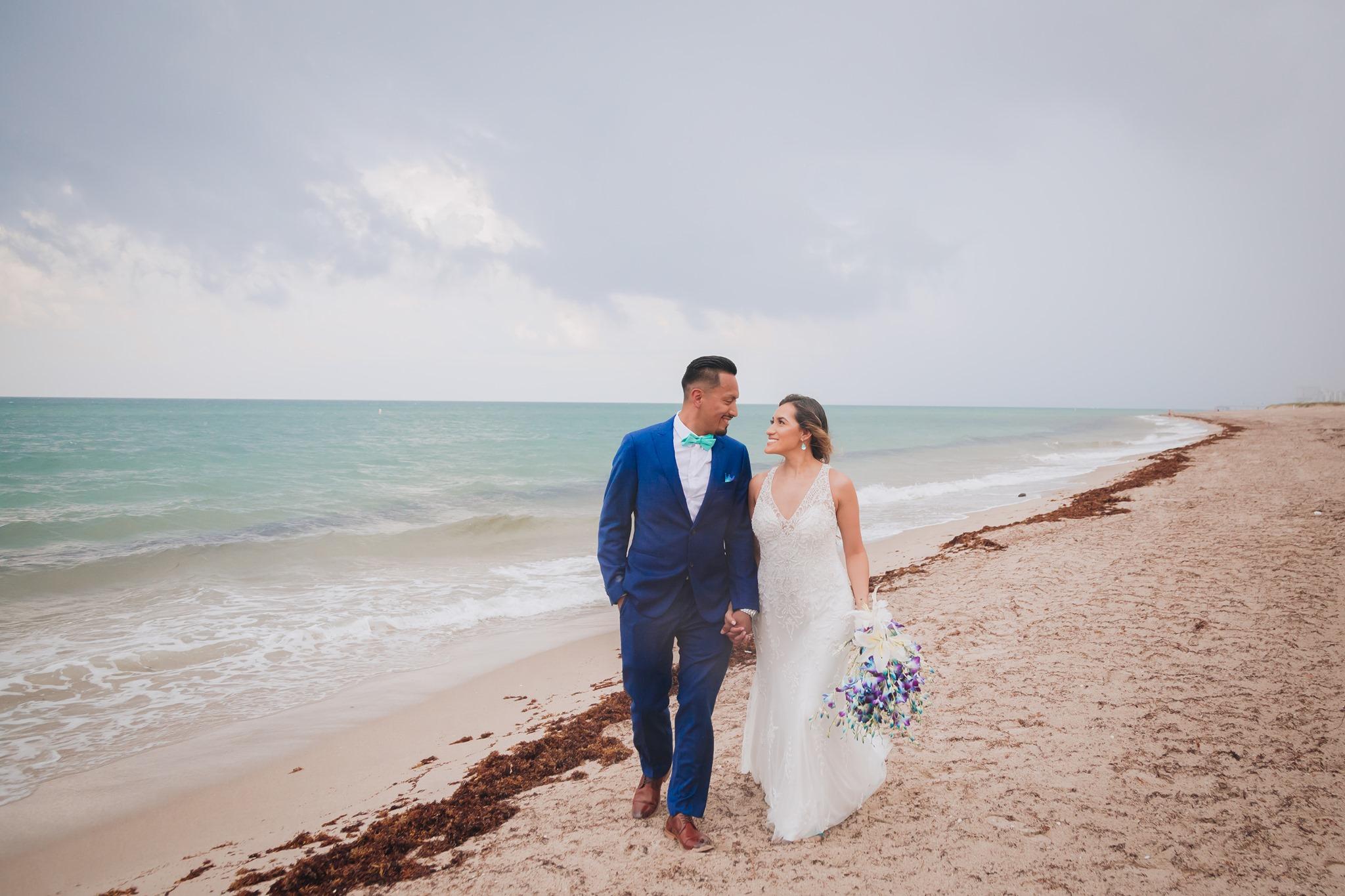 Bride and Groom Stroll along Pompano Beach, Gazing into each other's eyes